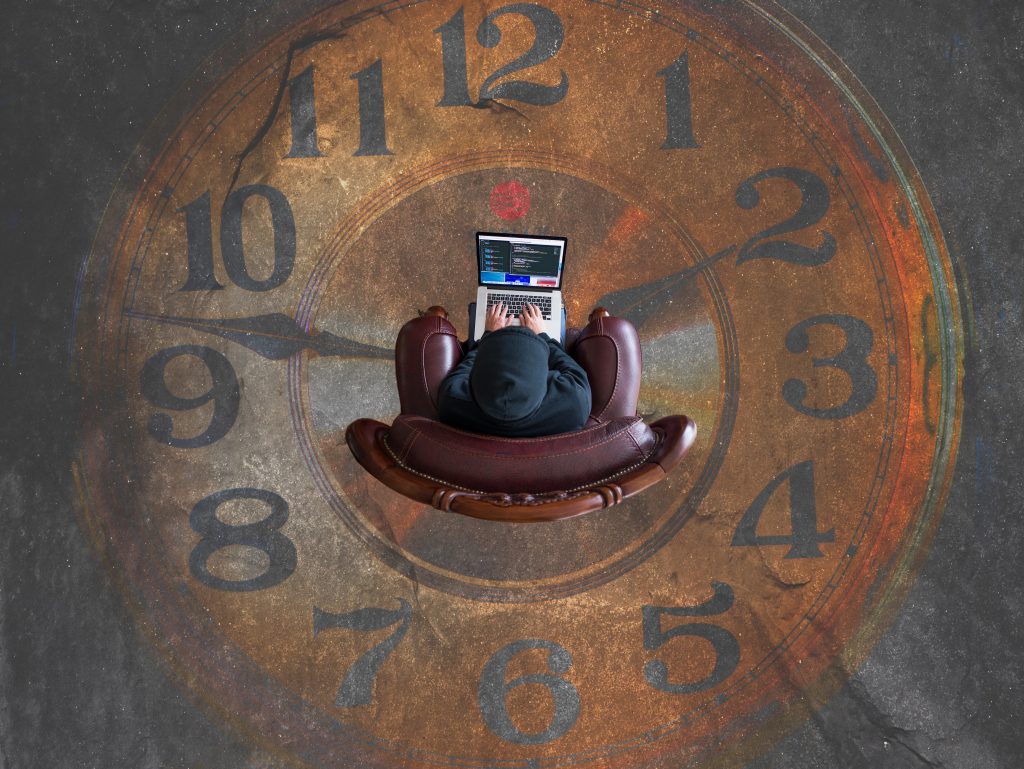 A person with a computer sitting inside a large clock